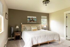 A bedroom with a bed, bedside lamps, a painting, and a window.