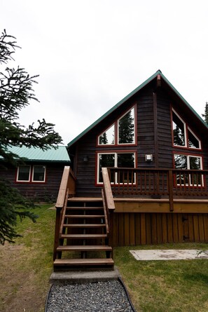 A wooden cabin with a wooden staircase leading to a deck.