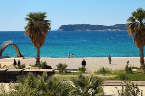 A beach with a clear view of the sea, palm trees, and a distinctive arch structure. - Hedera Estate, Hedera A59 (Dubrovnik)