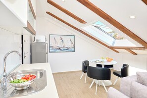 Una cocina moderna con tragaluces, un comedor con mesa y sillas, y vistas a veleros a través del tragaluz.