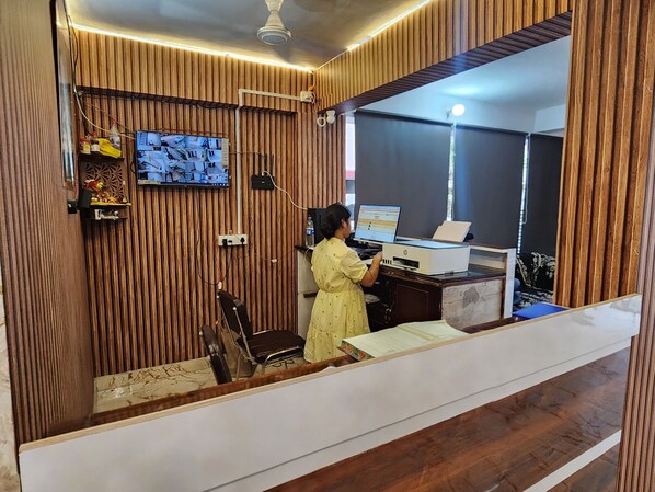 Una habitación con paneles de madera, un escritorio con computadora, una silla y un televisor montado en la pared.