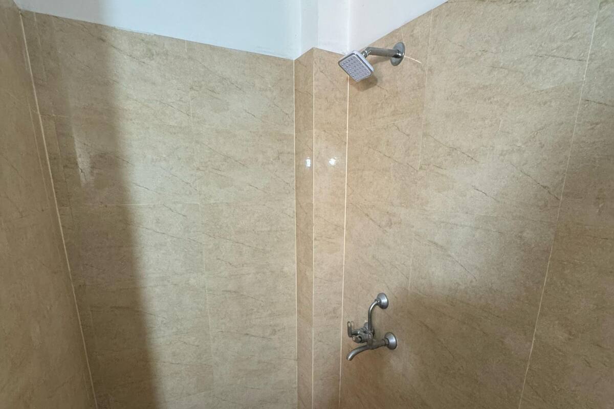 A small, tiled shower area with a handheld showerhead and a wall-mounted faucet.