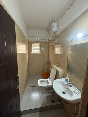 A small, compact bathroom with a toilet, sink, and shower. - The seven wonders 85 (Baruipur)