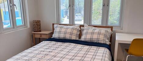 A bedroom with a bed, a desk, and a chair.