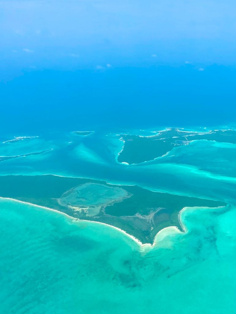 An aerial view of a coastal area with clear blue waters and distinct land formations.