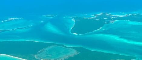 An aerial view of a coastal area with clear blue waters and distinct land formations.