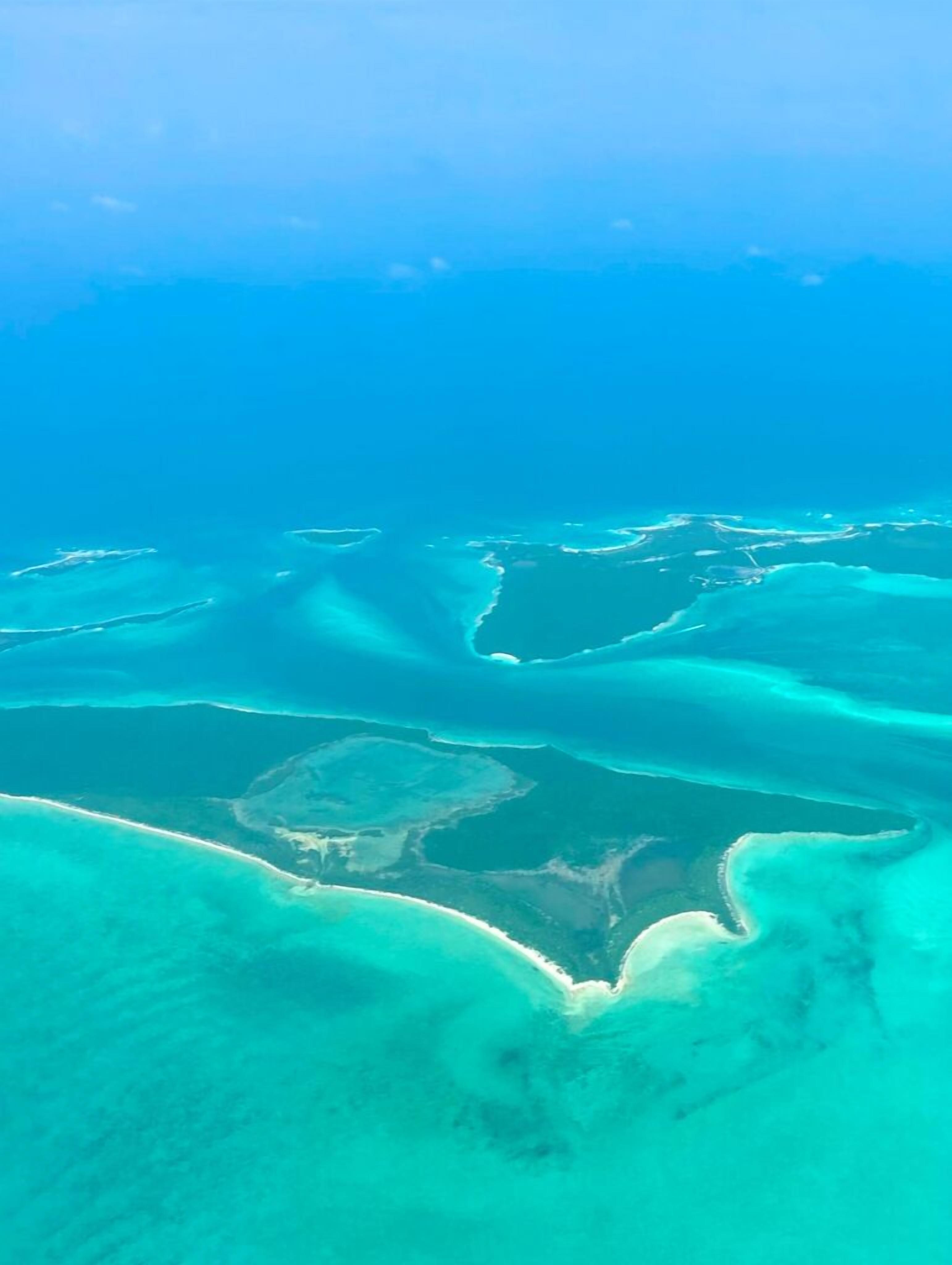 An aerial view of a coastal area with clear turquoise waters and a sandy beach.