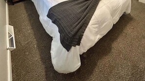 Une chambre à coucher avec un grand lit, un tableau au mur, une fenêtre avec des stores, une commode et un miroir.