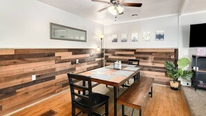 A dining area with a wooden herringbone wall, a ceiling fan, and a television on the right.