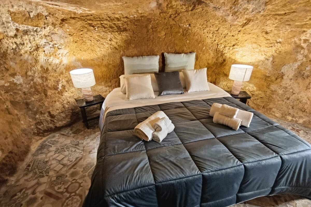 Ein Zimmer mit einem Bett, Kissen und zwei Nachttischen mit Lampen.