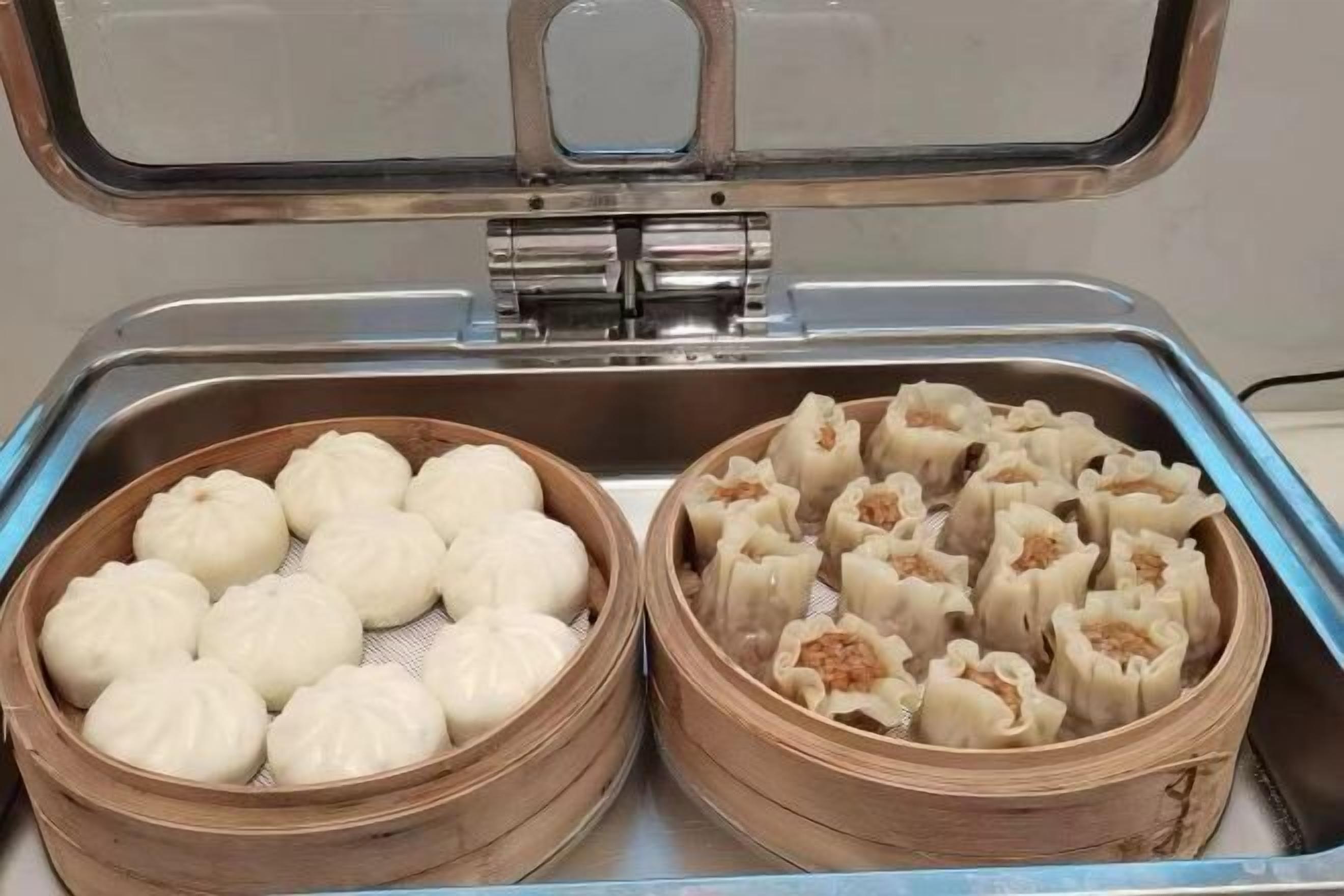 Dos vaporeras de bambú llenas de dumplings, una con dumplings simples y otra con dumplings rellenos de carne.