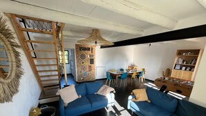 A cozy living room with a blue sofa, a coffee table, and a dining area with a table and chairs.
