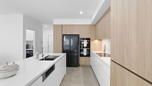 A modern kitchen with white cabinetry, a black refrigerator, and a built-in oven. - Stillwater on Stockton, 57B Stockton St - complete luxury in the heart of town (Nelson Bay)