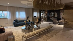 Un salón amplio con un sofá azul, un banco largo y una mesa de centro con jarrones decorativos.