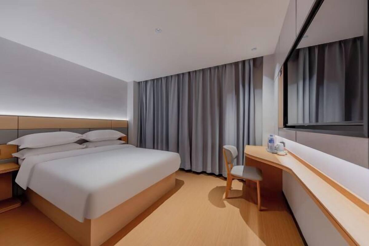 A modern hotel room with a bed, a desk, and a chair.