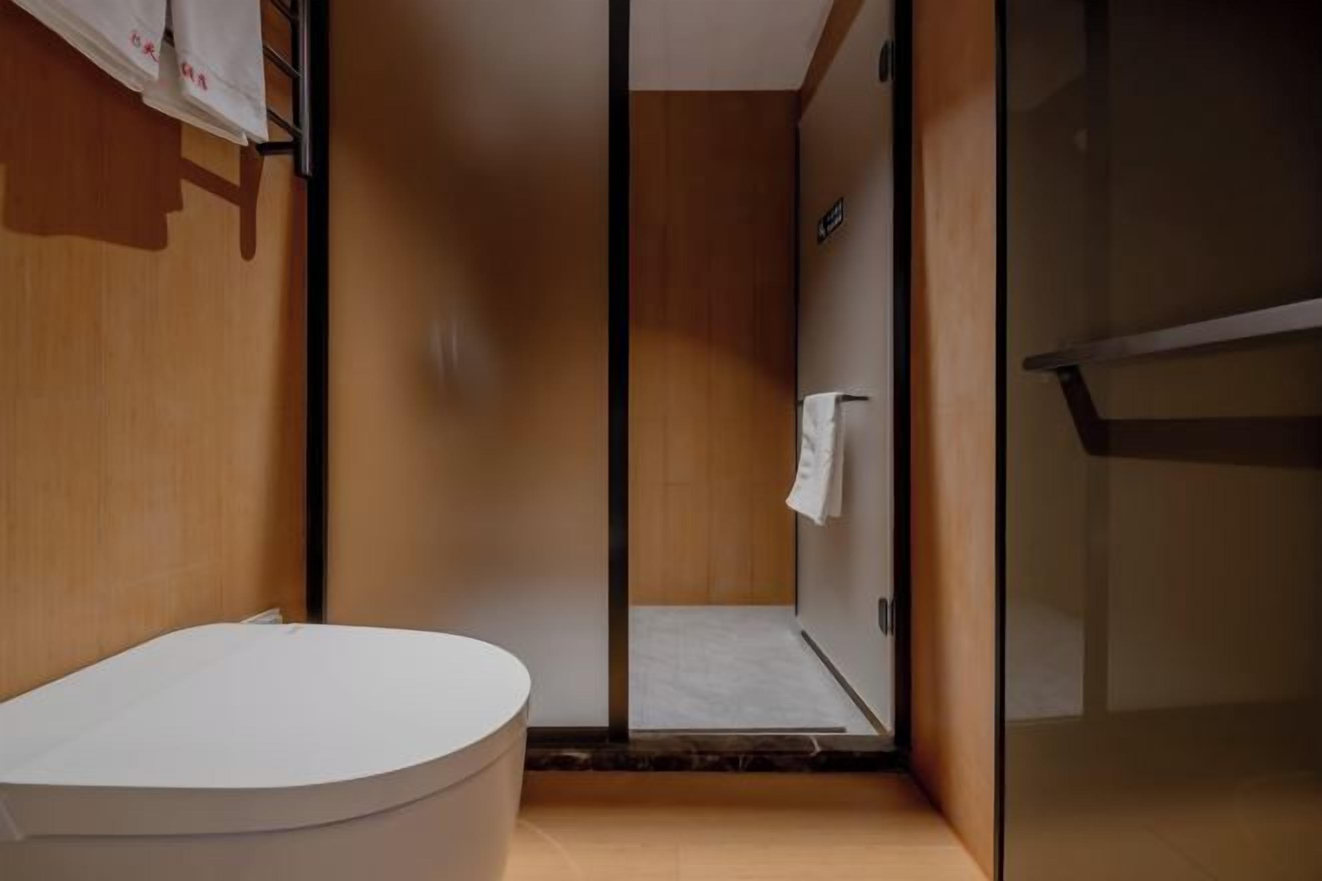 Un baño moderno con una bañera blanca, cabina de ducha de vidrio y paredes de madera.