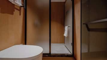 Un baño moderno con una bañera blanca, cabina de ducha de vidrio y paredes de madera.