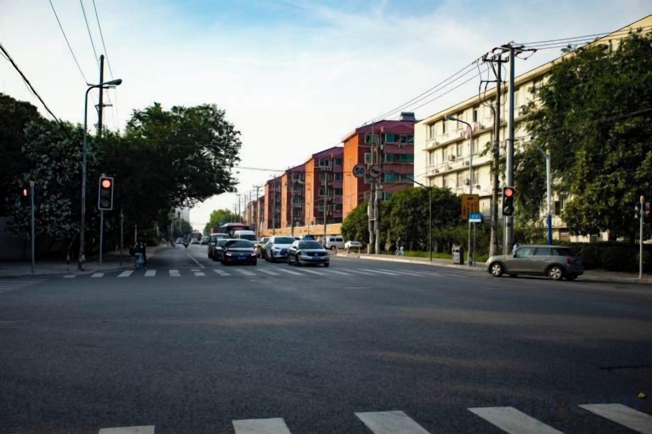 Liikennevaloin varustettu risteys, jossa on ajoneuvoja ja rakennuksia.
