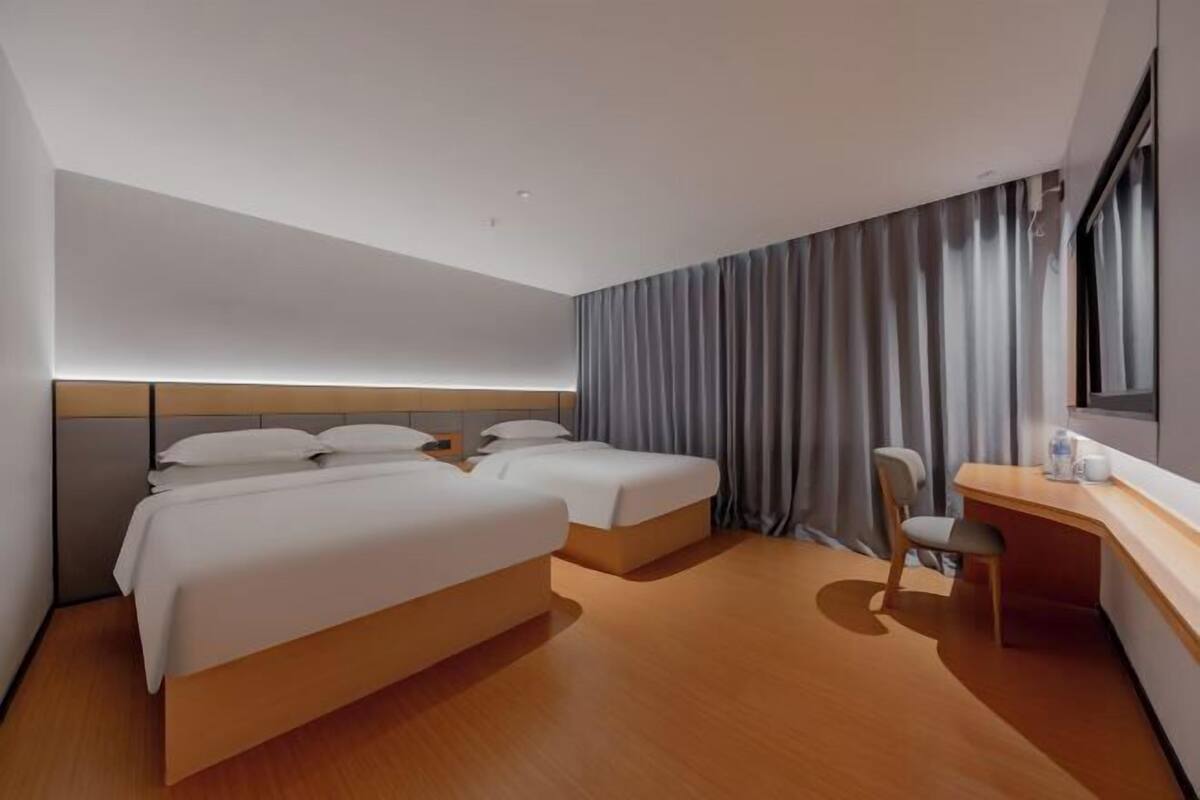 A modern hotel room with two beds, a desk, and a chair.