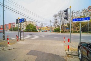 A street intersection with traffic lights, pedestrian crossing, and directional signs. - 8 Days Hotel (Minhang Jiaotong University Branch) (Shanghai)