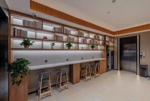 A modern kitchen with a long counter, bar stools, and a built-in bookshelf with plants. - 8 Days Hotel (Minhang Jiaotong University Branch) (Shanghai)