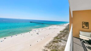 A balcony with a view of a beach and a pier. - Sterling Reef 905 (Panama City Beach)