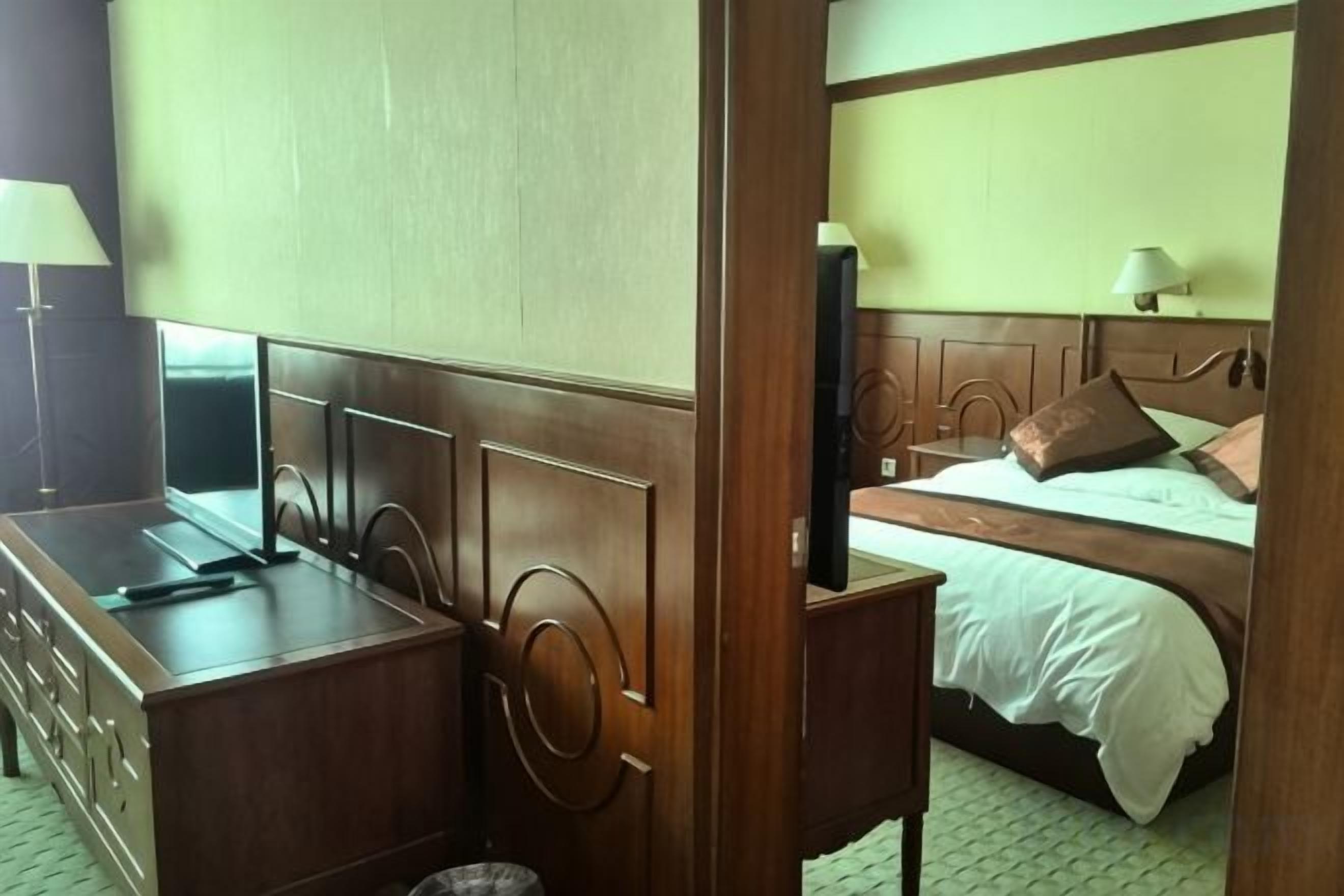 Habitació d'hotel amb llit de fusta, escriptori i televisió.