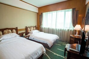 A hotel room with two beds, a desk with a lamp, and a large window with curtains. - Jinshan Hotel (Shanghai)