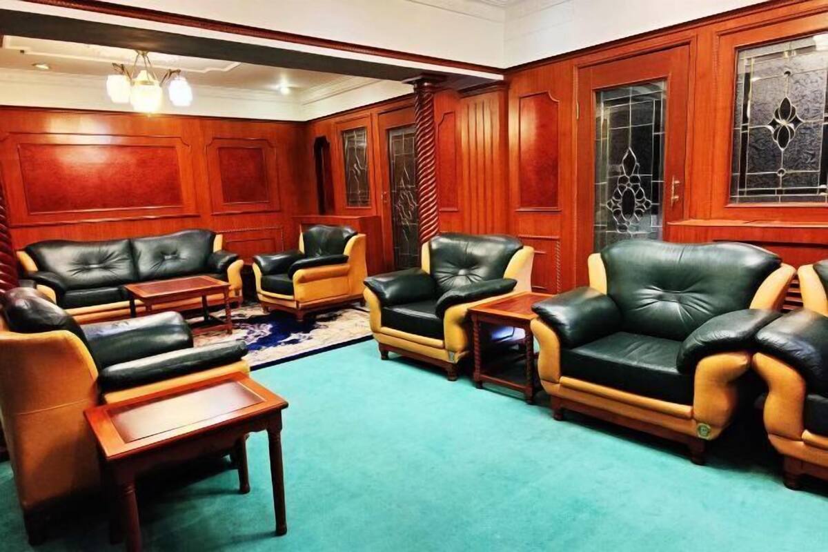 A room with wooden paneled walls, leather sofas, and a carpeted floor.