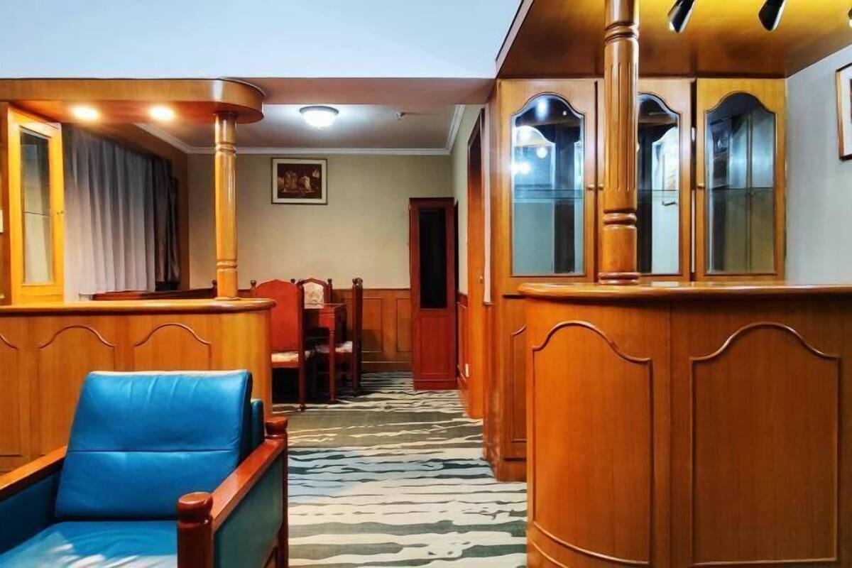 A hotel lobby with wooden paneling, a blue leather armchair, and a patterned carpet.