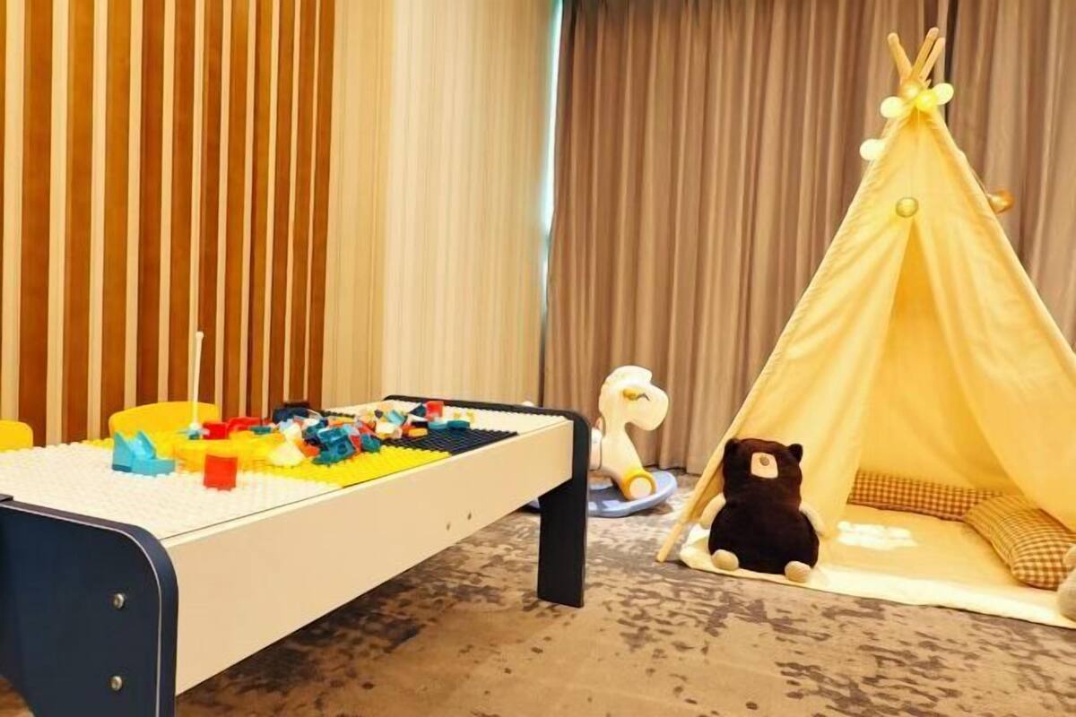 A child's play area with a bed, a play mat, a tent, and a stuffed animal.