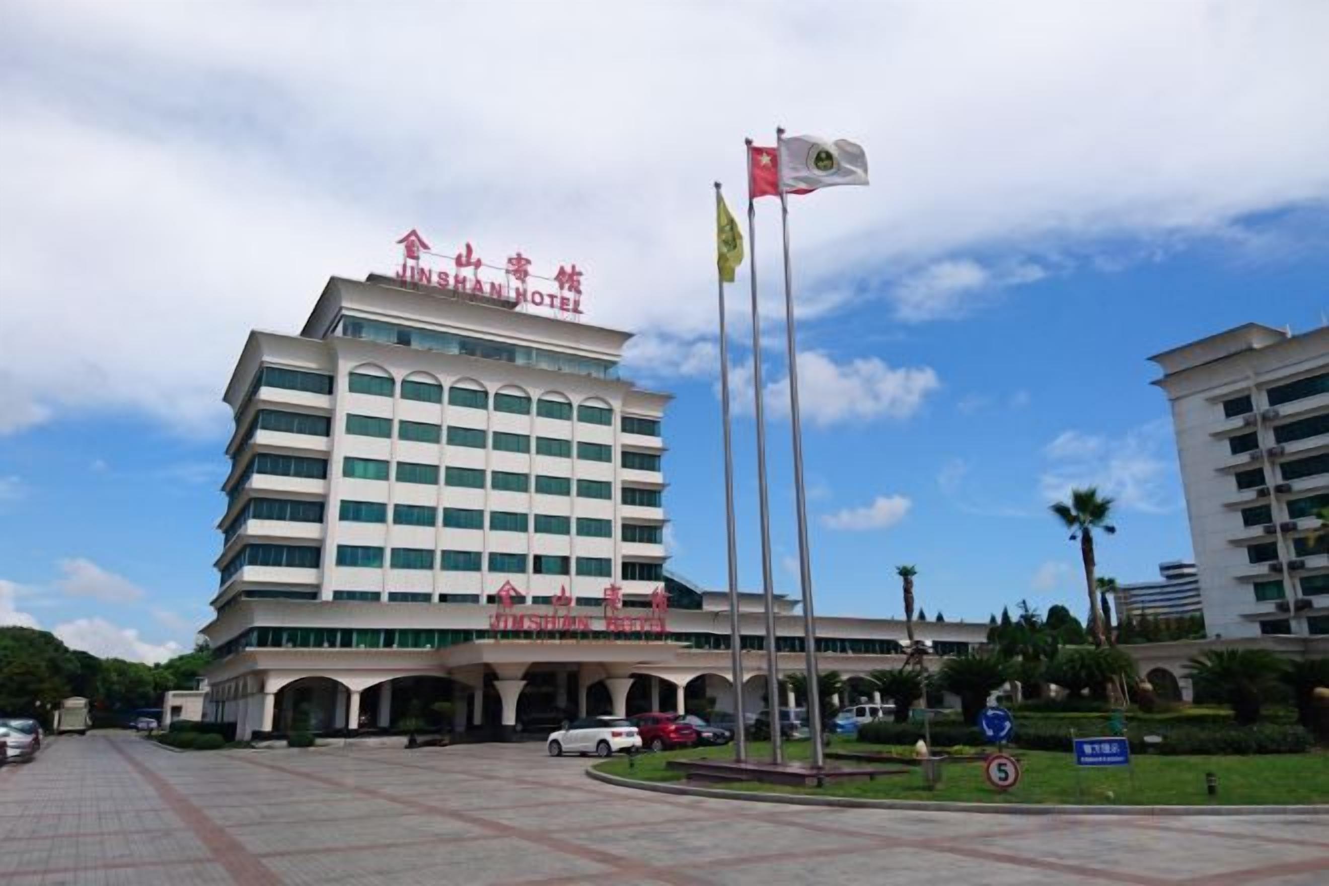 A multi-story hotel with a prominent signage, a flagpole, and a clear sky.