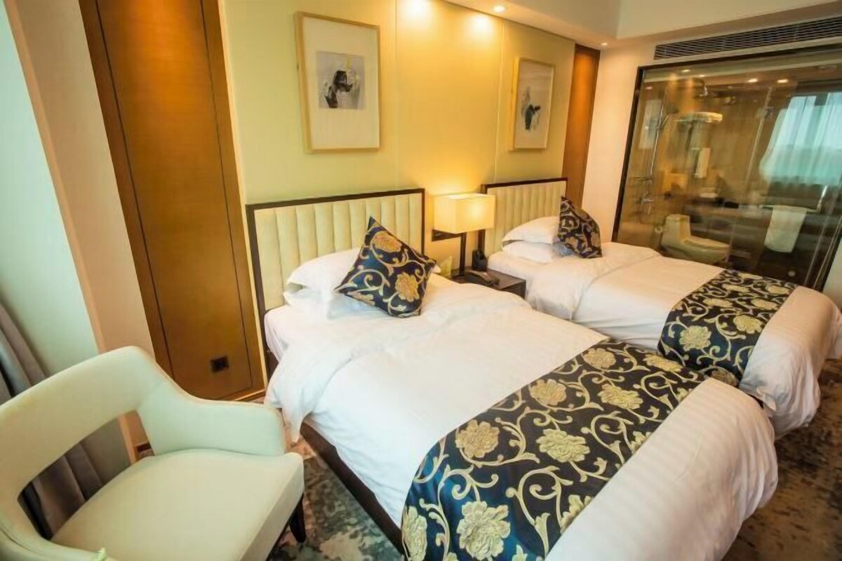 A hotel room with two beds, a chair, and a large mirror.