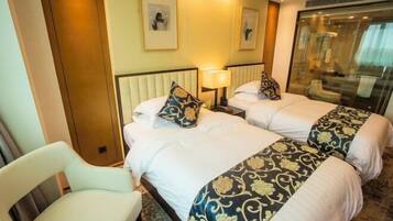 A hotel room with two beds, a chair, and a large mirror.