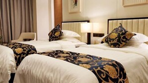 Camera d'albergo con due letti, una poltrona, una lampada e opere d'arte alle pareti.