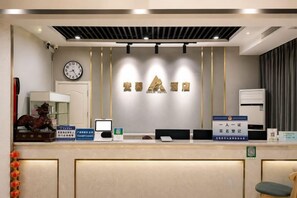 A hotel reception area with a reception desk, a clock, and a sign indicating a single room rate. - Anxin Express Hotel (Shijiazhuang New Railway Station East Plaza) (Shijiazhuang)