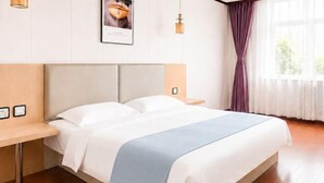 Una habitación de hotel con cama, mesitas de noche, una ventana con cortinas e iluminación en la pared.