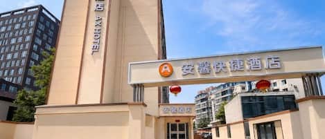 A hotel entrance with a vertical sign and a horizontal sign above the door.