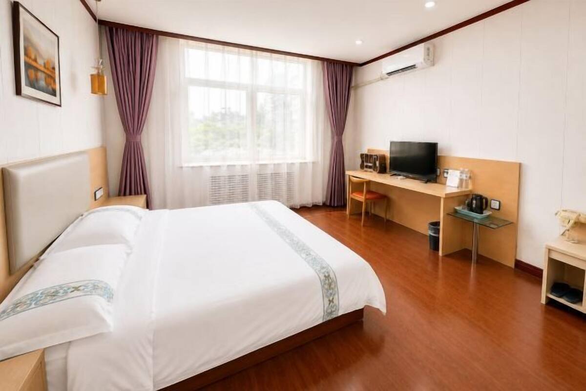 Een hotelkamer met een bed, een bureau met een televisie en een raam met gordijnen.