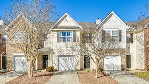 A row of two-story townhouses with attached garages, a clear driveway, and a well-maintained lawn. - Spacious Retreat Near RDU ~ Pool, BBQ, Fast Wi-Fi & Easy Self Check-In (Morrisville)