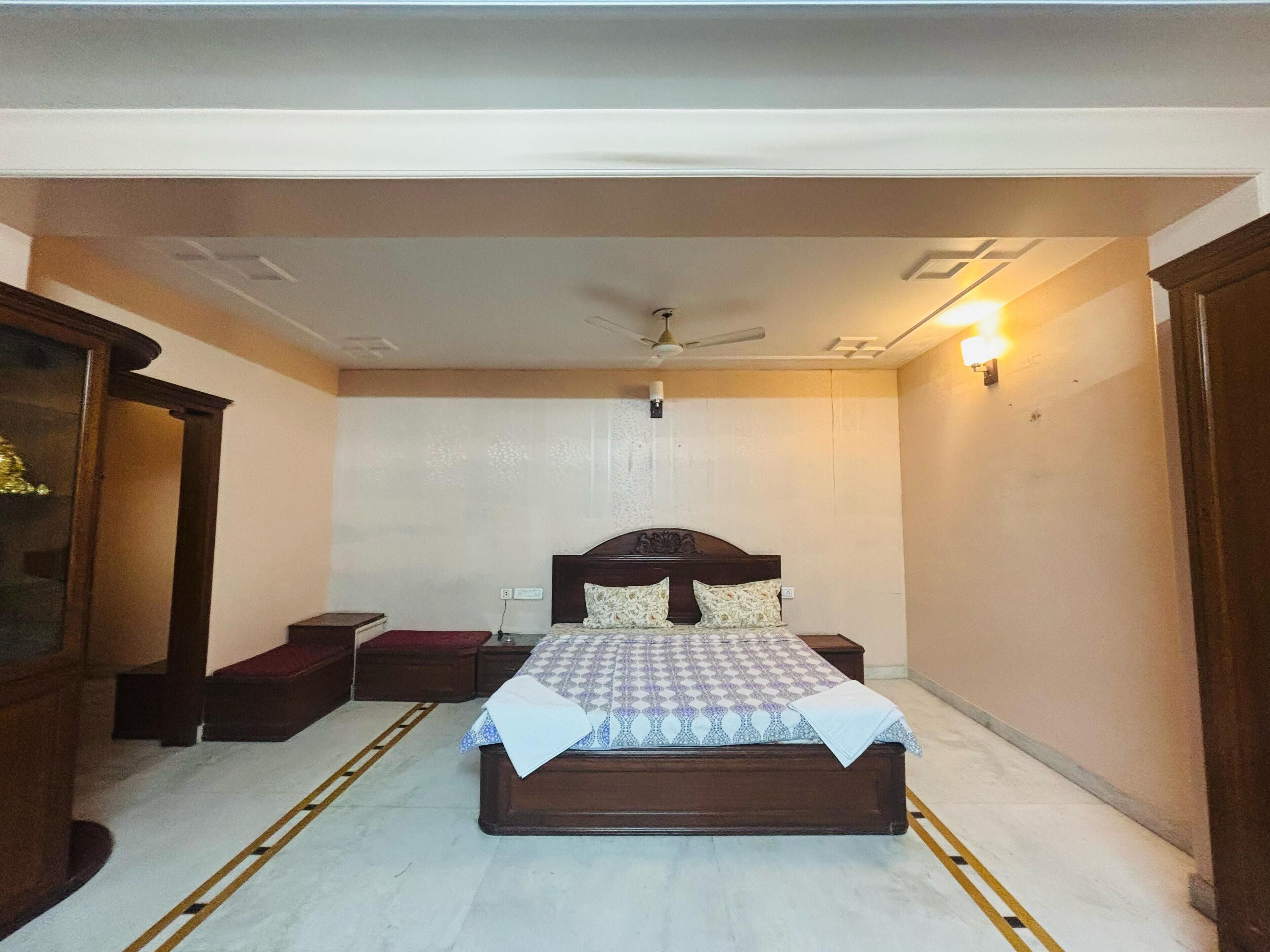 A bedroom with a bed, bedside tables, a nightstand, a ceiling fan, and a wall-mounted light fixture.