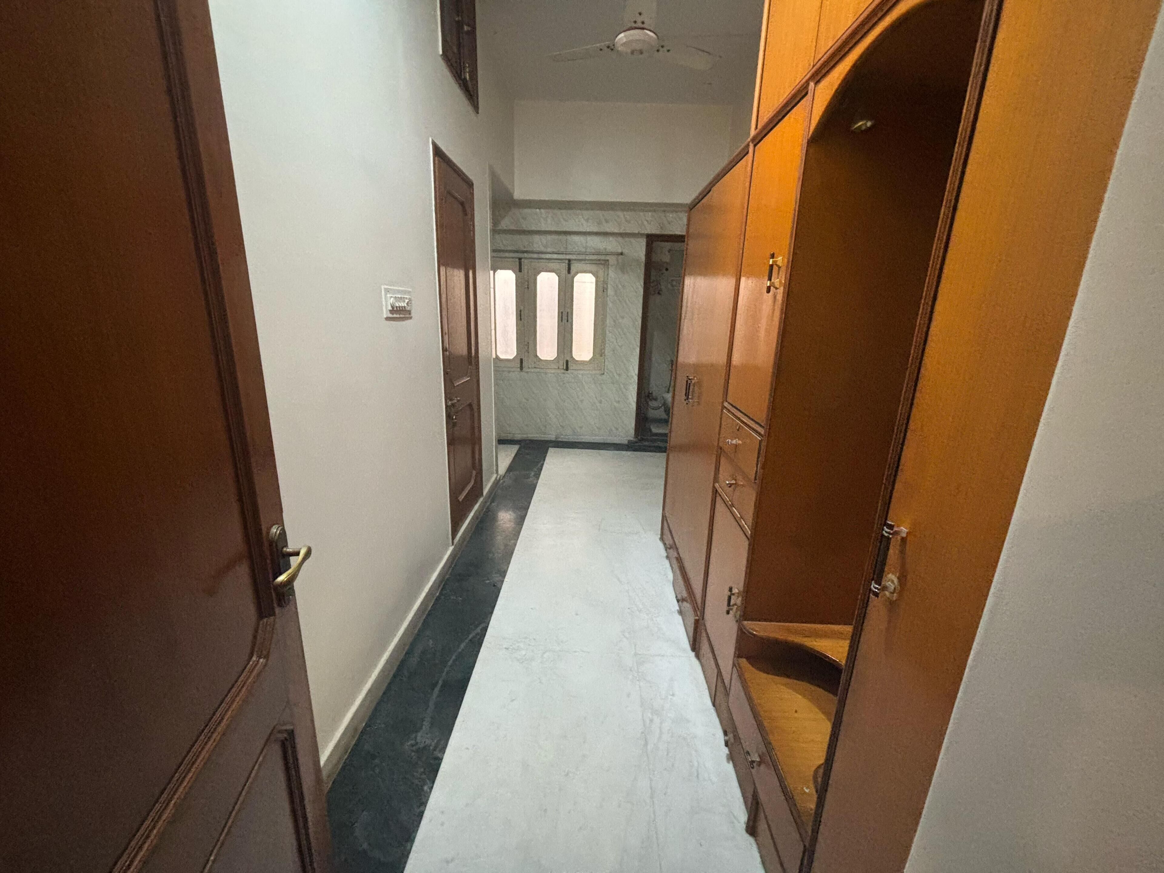 A hallway with wooden doors, a marble floor, and a ceiling fan.