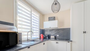 Eine moderne Küche mit weißen Schränken, einer schwarzen Arbeitsplatte, einer Mikrowelle, einem Wasserkocher und einem Schild mit dem Hinweis zum Home-WLAN-Passwort.