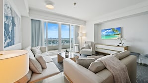 A modern hotel room with a large window, a sofa, a chair, a desk, and a painting on the wall. - Ritz-Carlton Luxury 1BR Residence - Beachfront (Fort Lauderdale)