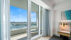 A modern hotel room with a large sliding glass door leading to a balcony with a city view. - Ritz-Carlton Luxury 1BR Residence - Beachfront (Fort Lauderdale)