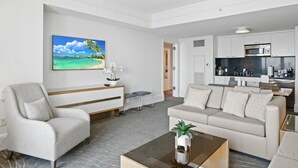 A modern living room with a sofa, armchair, and coffee table. A painting of a beach scene is on the wall. - Ritz-Carlton Luxury 1BR Residence - Beachfront (Fort Lauderdale)