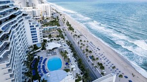 A coastal hotel with a beachfront, a swimming pool, and a road running parallel to the beach. - Ritz-Carlton Luxury 1BR Residence - Beachfront (Fort Lauderdale)