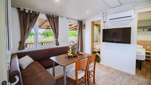 A compact living space with a sofa, dining table, and TV. - Waterside Retreat Mobile Homes With Thermal Riviera Tickets (Brežice)
