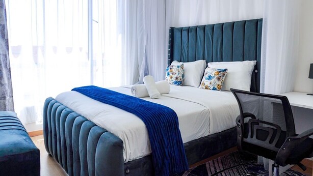 A modern bedroom with a large bed, a desk, and a chair. - Lux Suites Riara One Residency Kilimani (Nairobi)