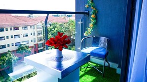 A balcony with a white table, a chair, and a vase of red flowers. - Lux Suites Riara One Residency Kilimani (Nairobi)